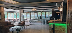An open-plan restaurant with high ceilings, large windows, and a mix of seating arrangements including tables and chairs. - Royal Park Hotel Corlu (Corlu)