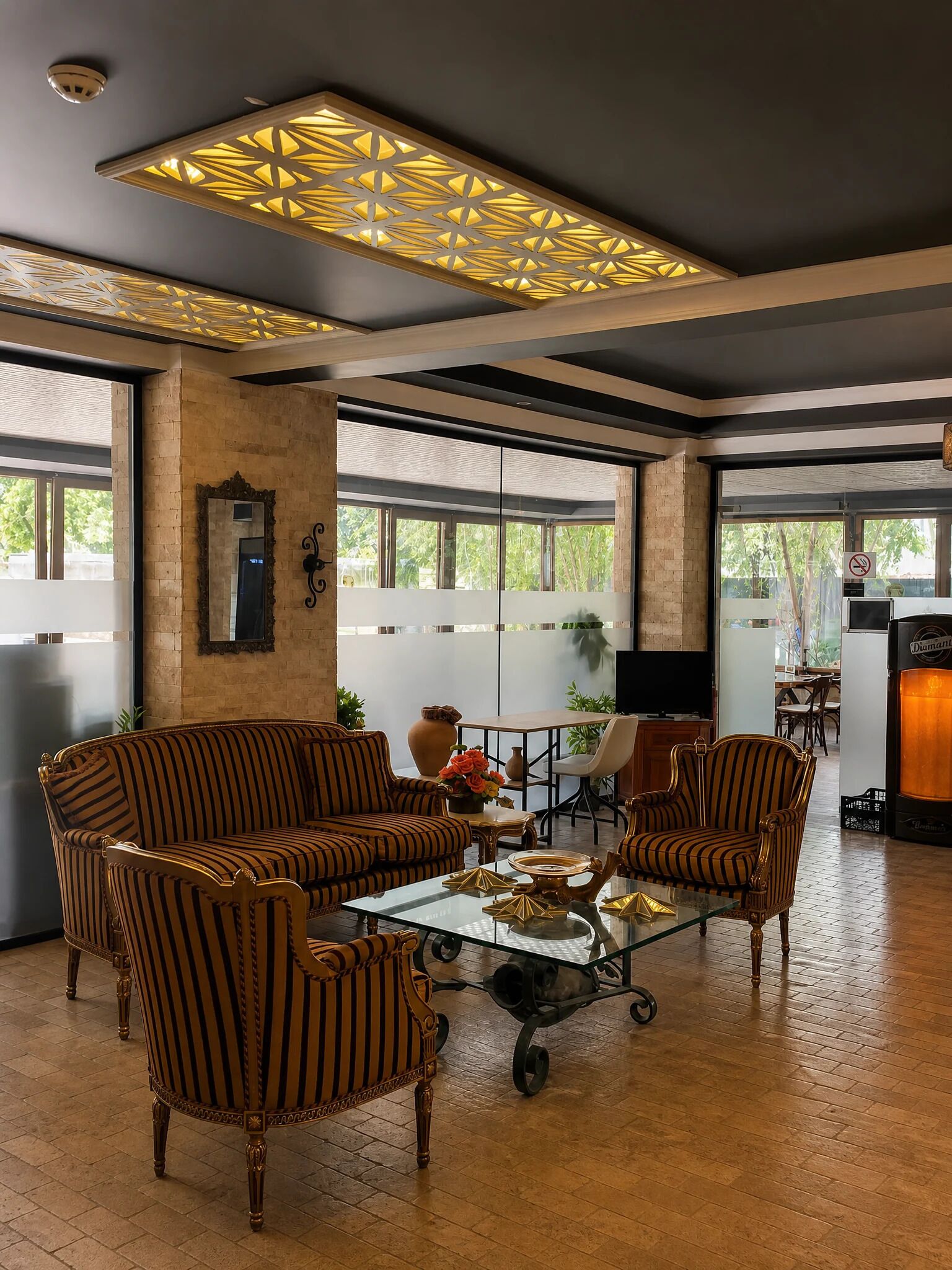 Un amplio salón con sofás a rayas, una mesa de centro de cristal y una lámpara decorativa en el techo.