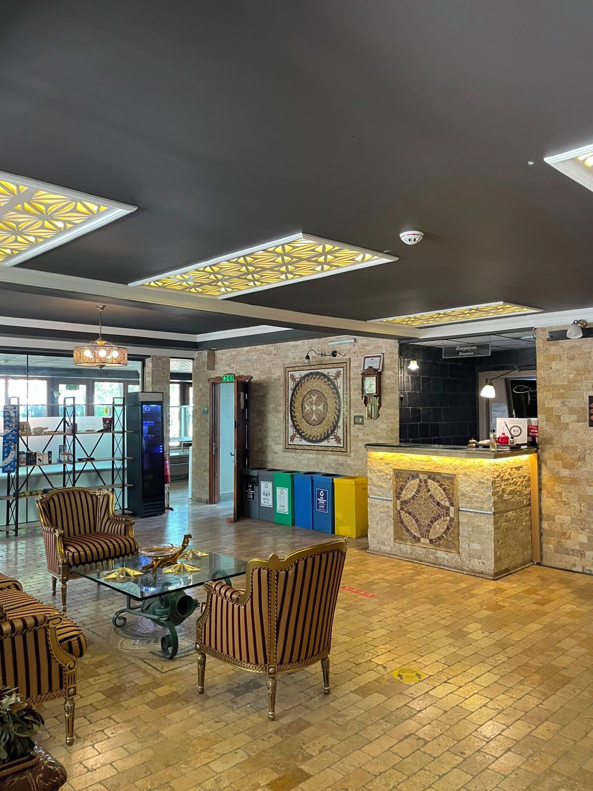 Una hall con poltrone a righe, una reception e un soffitto decorativo.