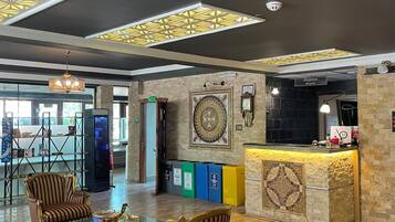 Una hall con poltrone a righe, una reception e un soffitto decorativo.