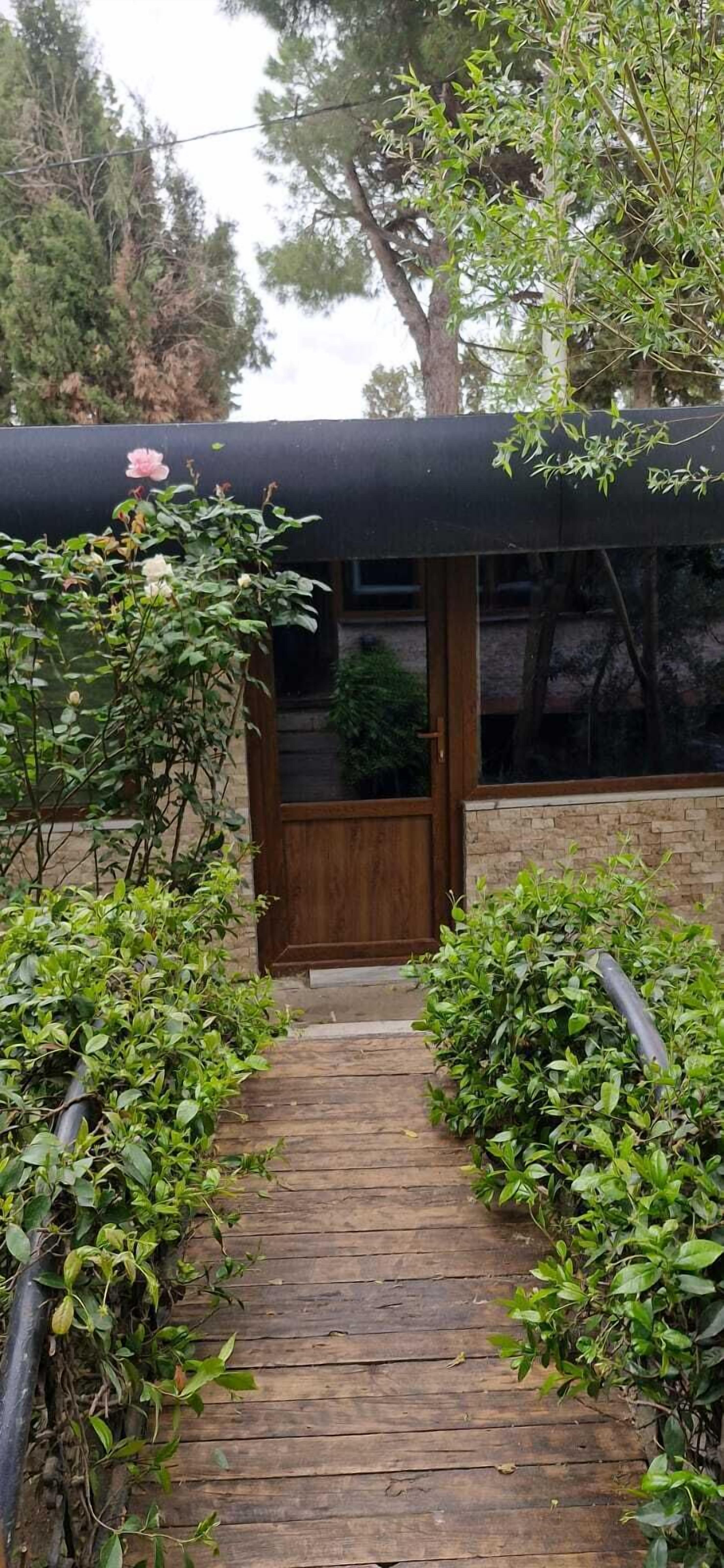 Un camí de fusta que condueix a una porta de fusta sota una tenda negra.