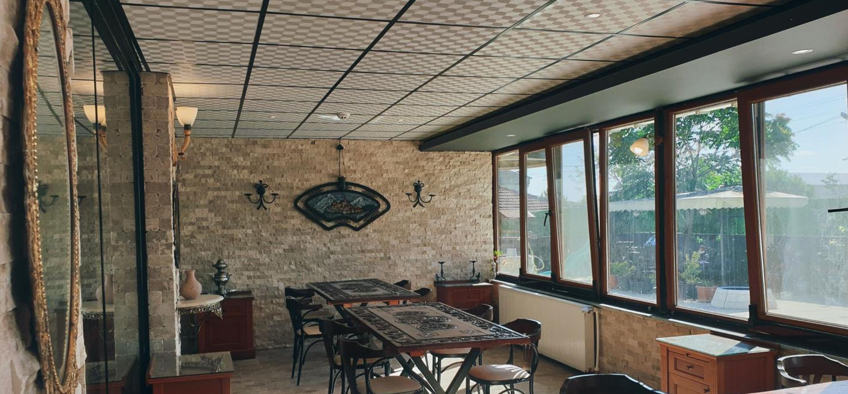 Un espace repas avec un mur en briques, de grandes fenêtres et une table entourée de chaises.