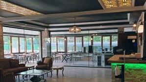A spacious indoor area with a mix of seating arrangements, large windows, and a bar area. - Royal Park Hotel Corlu (Corlu)