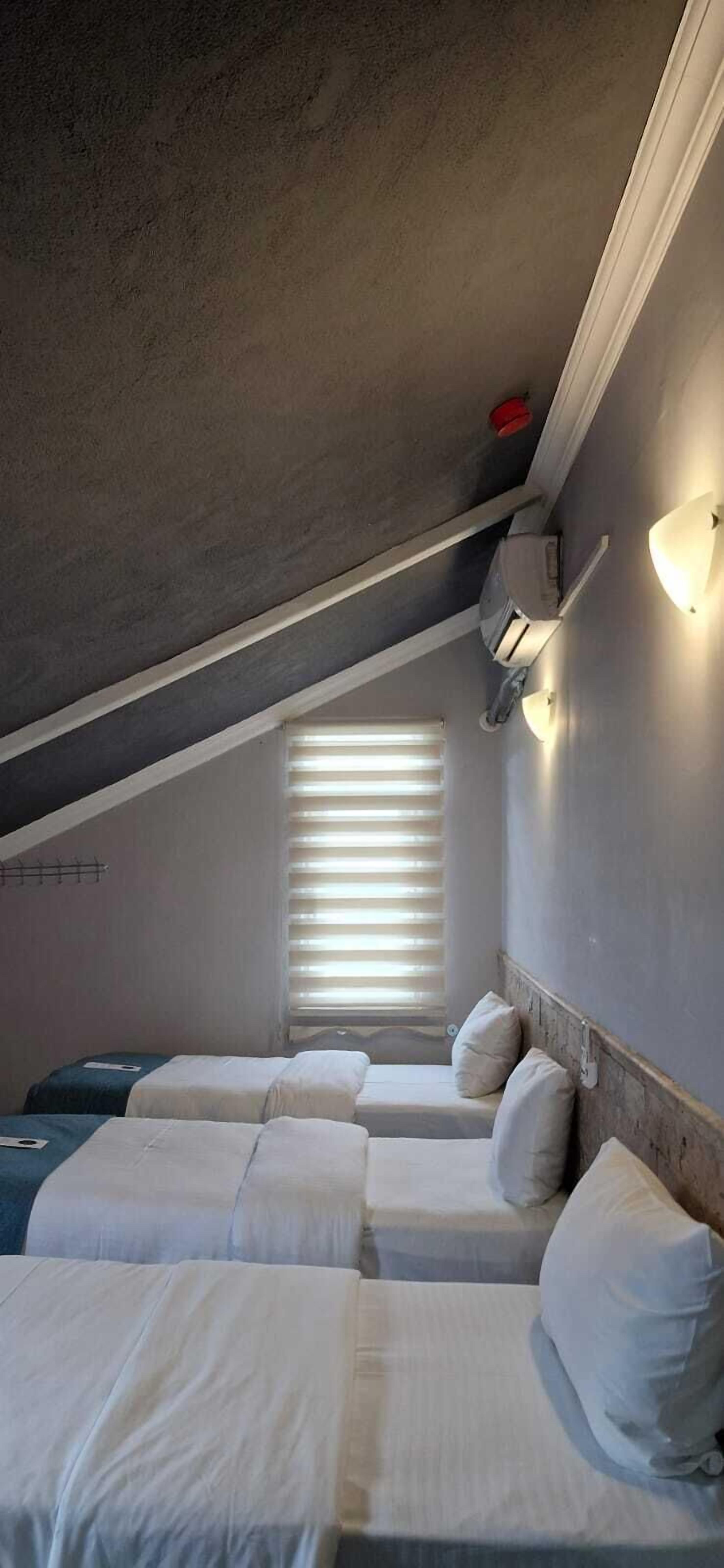 Un dormitorio con dos camas, una ventana con persianas, un calentador en la pared y una rejilla en el techo.
