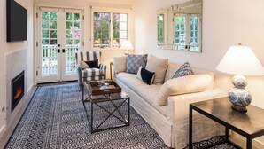 A living room with a sofa, armchair, coffee table, fireplace, and a patterned rug.