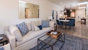 A modern living room with a sofa, coffee table, and dining area.