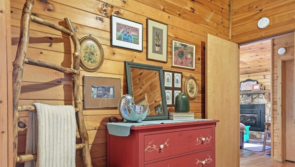A wooden interior with a red dresser, framed pictures, a mirror, and a fireplace. - Riverside Nest, No Pet Fees, Sleeps 2, Adults Only, River front (Ellijay)