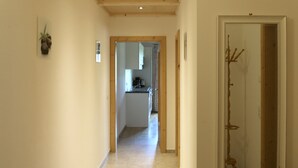 Un couloir avec un plafond en bois, un miroir encadré et une plante en pot.