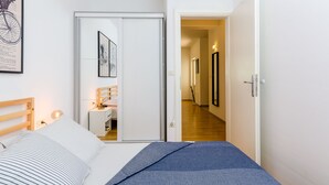 Makuuhuoneessa on sänky, yöpöytä, lamppu ja ovi, joka johtaa käytävään.