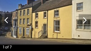 A row of traditional buildings with a mix of architectural styles, including a yellow building with a visible staircase and a white building with a window. - Beautiful 2 bedroom spacious Cottage in the heart of historic Richmond  (Richmond)