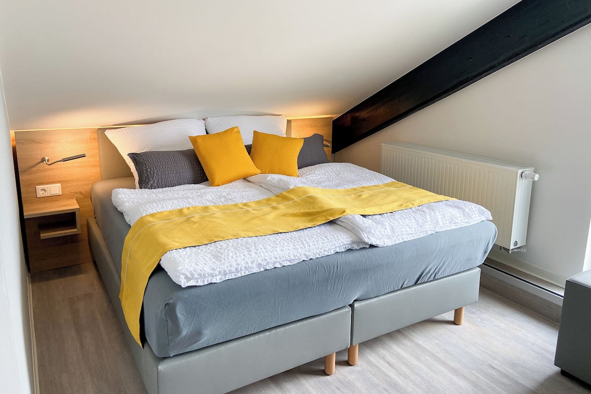 Une chambre à coucher moderne avec un lit, des tables de chevet, une commode et un radiateur.