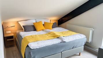 A modern bedroom with a bed, bedside tables, a nightstand, and a radiator.