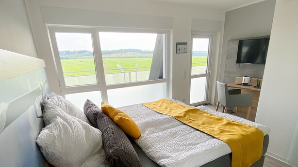 A modern bedroom with a bed, a desk, and a TV.