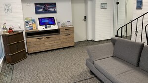 A reception area with a computer kiosk, a couch, a wooden cabinet, and a fire extinguisher.