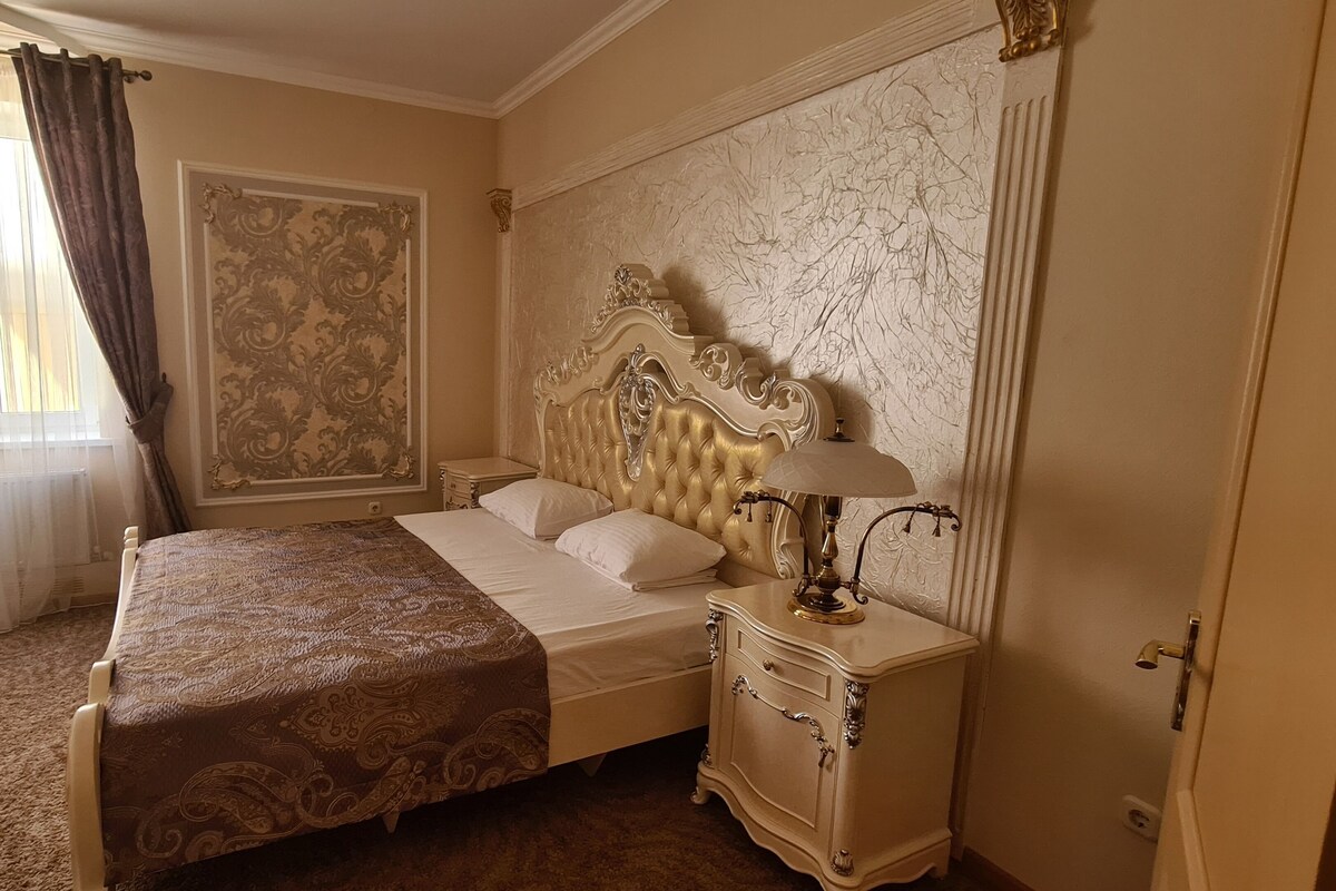 Une chambre à coucher classique, avec un grand lit, une table de chevet et une lampe fixée au mur.