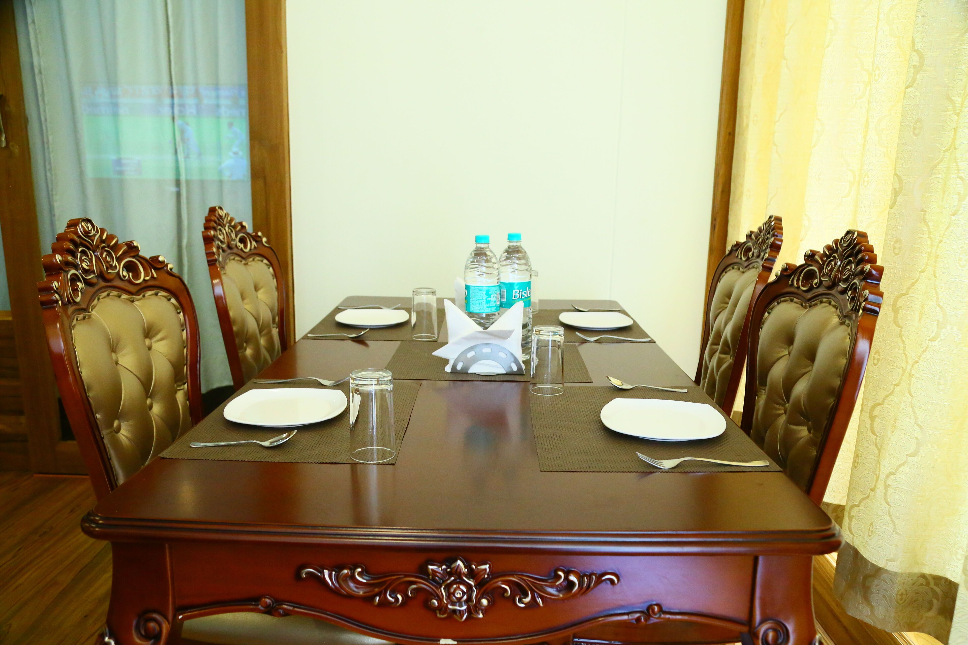 A dining table set for four with water bottles, plates, and cutlery.