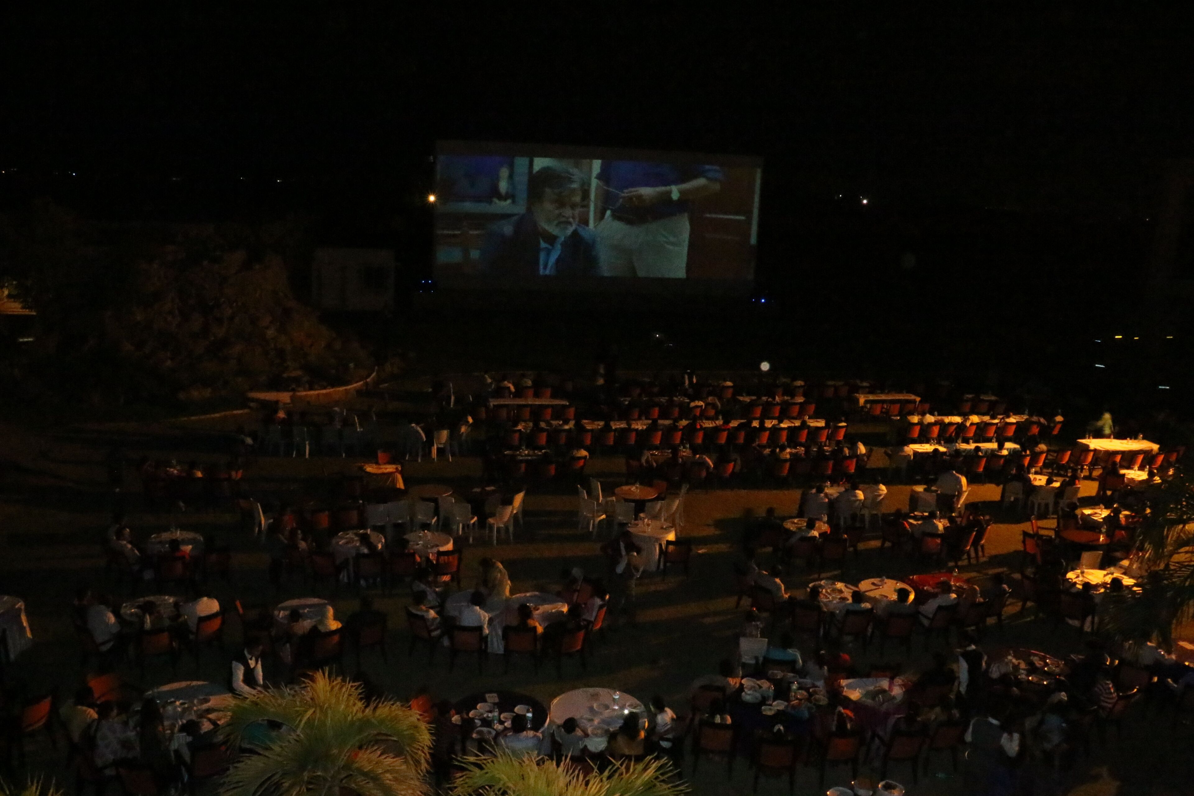Een groot openluchtcinema met rijen zitplaatsen gericht op een scherm.