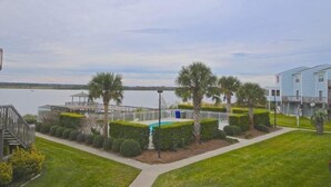 Un quartier résidentiel doté d’une piscine, de palmiers et offrant une vue sur un lac.