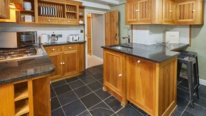 A kitchen with wooden cabinets, a granite countertop, a sink, and a stove. - Host & Stay | Henderson House (Whitby)