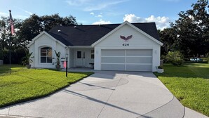 A single-story house with a garage, a front yard, and a flagpole. - Private Pool, HotTub and Golf Cart in the Village of Rio Grande! (The Villages)