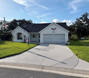 Ein einstöckiges Haus mit Garage, Vorgarten und Fahnenmast.