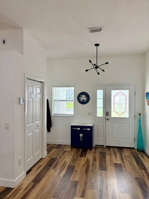 A hallway with a wooden floor, white doors, a blue cabinet, and a ceiling light fixture.