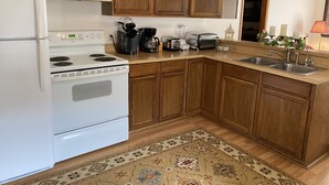 Una cucina con mobili in legno, un fornello bianco, un lavello e diversi elettrodomestici.