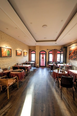 Un restaurante con paredes de ladrillo, pisos de madera y mesas con manteles rojos.