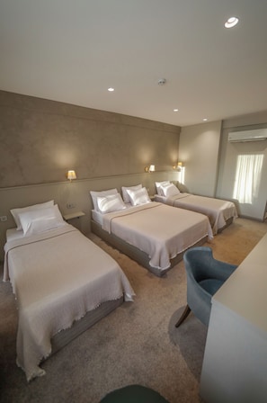 Una habitación de hotel con dos camas, un escritorio, una silla y una ventana con cortinas.