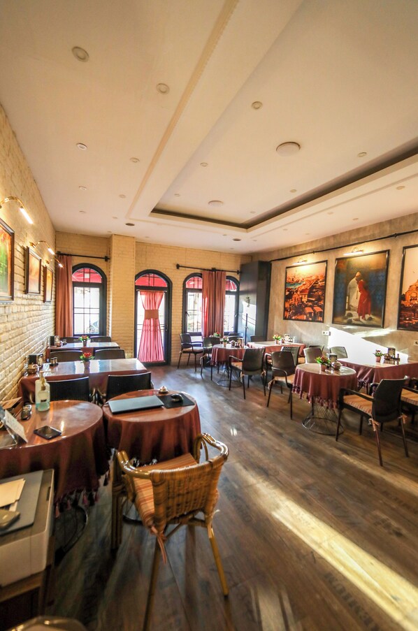 Un restaurante con mesas redondas, sillas y una pared de ladrillo.