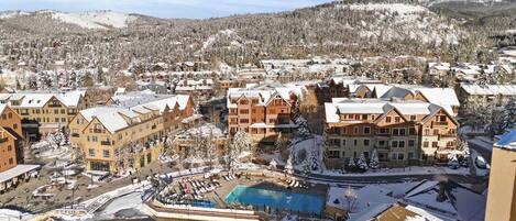 Un resort con varias construcciones, una piscina y montañas al fondo.