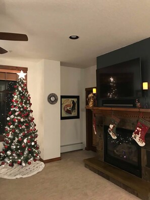 Ein Wohnzimmer mit Weihnachtsbaum, Kamin und Fernseher.