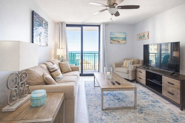 A modern living room with a sofa, coffee table, TV, and a balcony with a view.