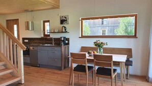 A cozy kitchen with wooden cabinets, a dining table with chairs, and a large window.