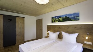 Een slaapkamer met een groot bed, een houten hoofdbord en een schilderij van een landschap aan de muur.
