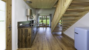 Een moderne keuken met houten vloeren, een inbouwfornuis en uitzicht op de omgeving door grote ramen.
