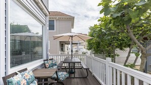 A covered outdoor deck with a table and chairs, a white picket fence, and a view of a neighboring house. - Atlantic City ☆Waterfront Park☆ Amazing 360 views (Atlantic City)