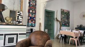 A room with a brown leather chair, a green door, and various artworks on the walls.