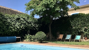 A swimming pool with a clear blue water surface, surrounded by lush greenery and trees.