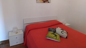 A bedroom with a white bed, red bedding, and three decorative pillows. - Accommodation in villa with large panoramic terrace (Imperia)