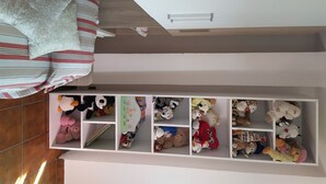 A child's bedroom with a bed, a white wardrobe, and a shelf filled with stuffed toys. - Accommodation in villa with large panoramic terrace (Imperia)
