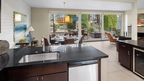 A modern kitchen with a central island, a dining area with outdoor seating, and a large sliding glass door leading to a patio. - Mid Century Modern-Stunning Mountain Views, Quiet, Clean, Bright & Open Design. (Indian Wells)