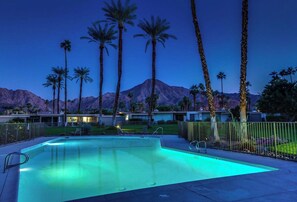 Relax by the pool surrounded by lush palm trees and a distant mountain view.