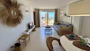 Uma sala de estar moderna com sofá, televisão e área de refeições.