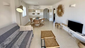 Uma sala de estar moderna com sofá, mesa de centro, TV e área de jantar.