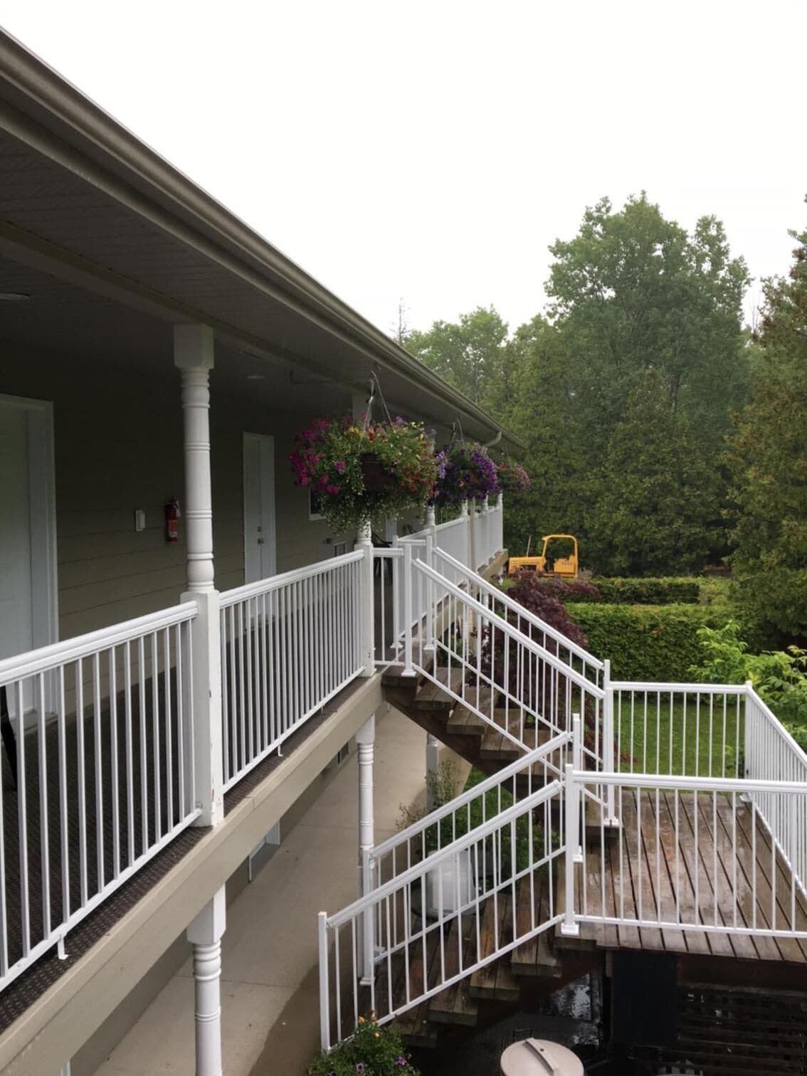 Une maison à deux étages avec un porche couvert, des balustrades blanches et un petit escalier extérieur.