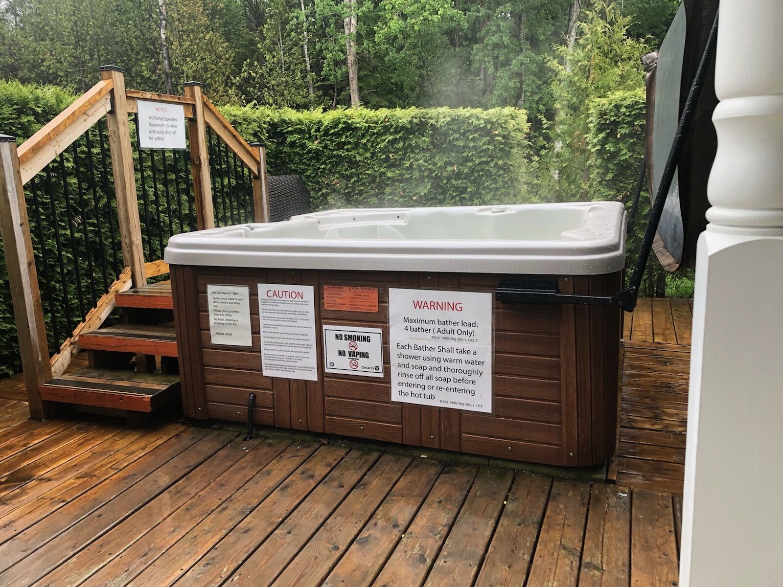 A hot tub with wooden steps leading up to it, surrounded by greenery.
