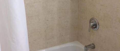A bathroom with a bathtub, a showerhead, and a toilet.