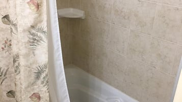 A bathroom with a bathtub, tiled walls, and a shower curtain with a floral pattern.