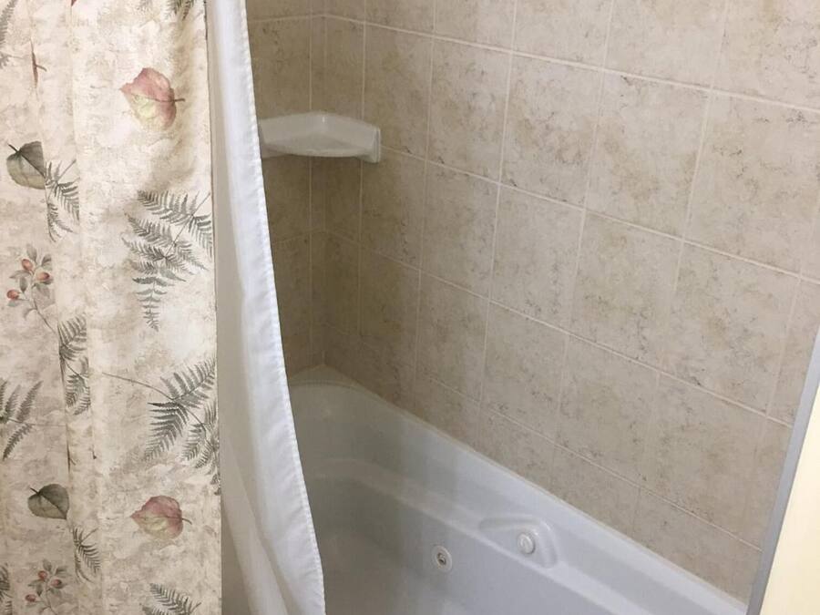 A bathroom with a bathtub, tiled walls, and a shower curtain with a floral pattern.